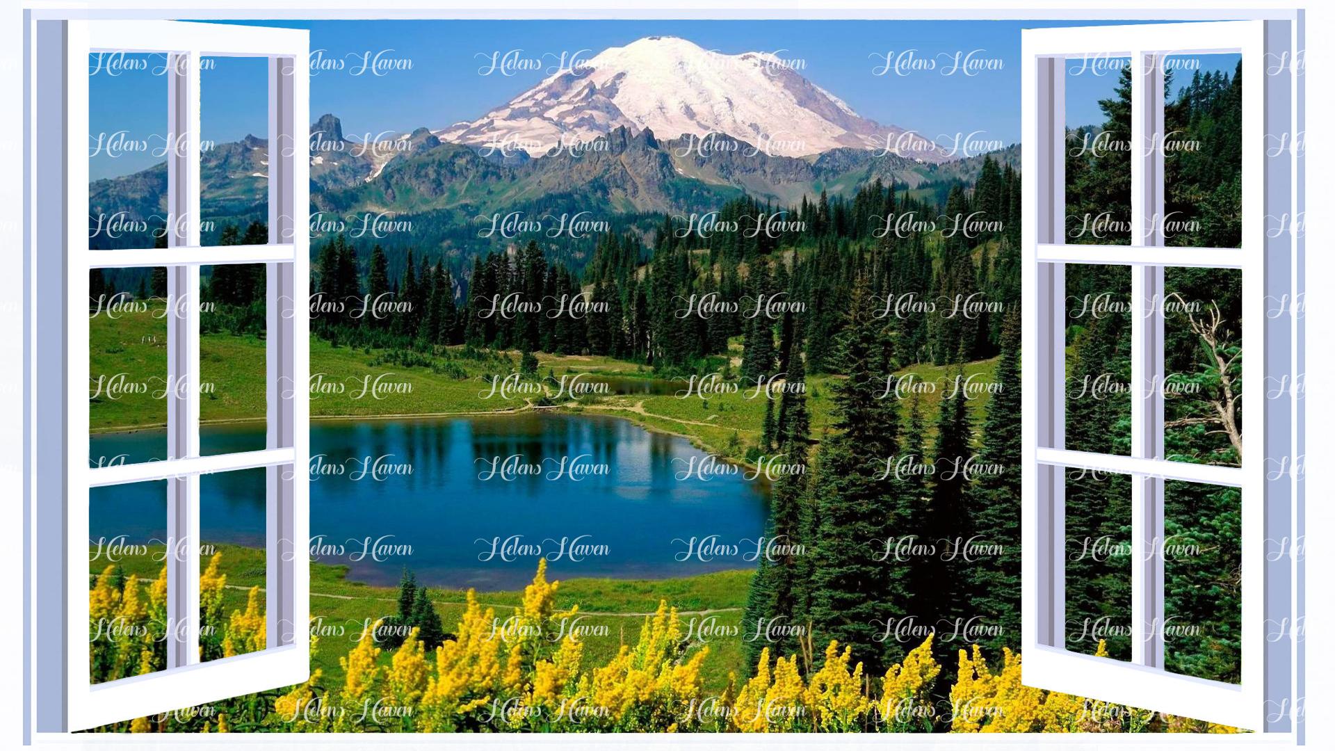 Looking out of a window at a snow covered mountain with a lake and green fields in the foreground