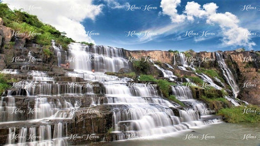 A terraced rock waterfall cascades down a series of rugged, tiered ledges, creating a dramatic and visually stunning natural feature.