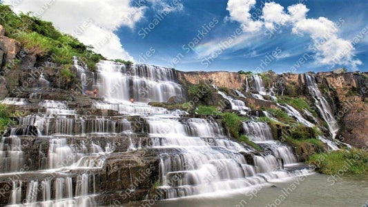 A stunning waterfall with a blue sky dotted with clouds