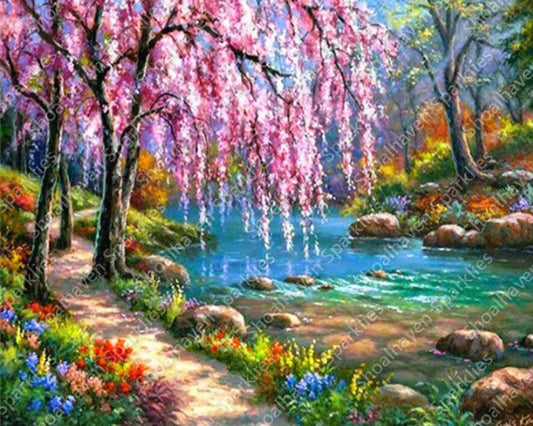 A weeping cherry blossom tree sits alongside a path that winds along a river